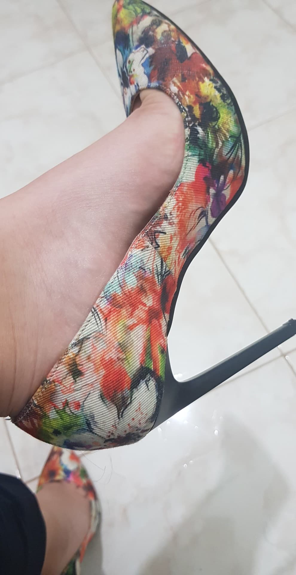 Clearly adult foot in a colorful patterned stiletto shown in close-up.
