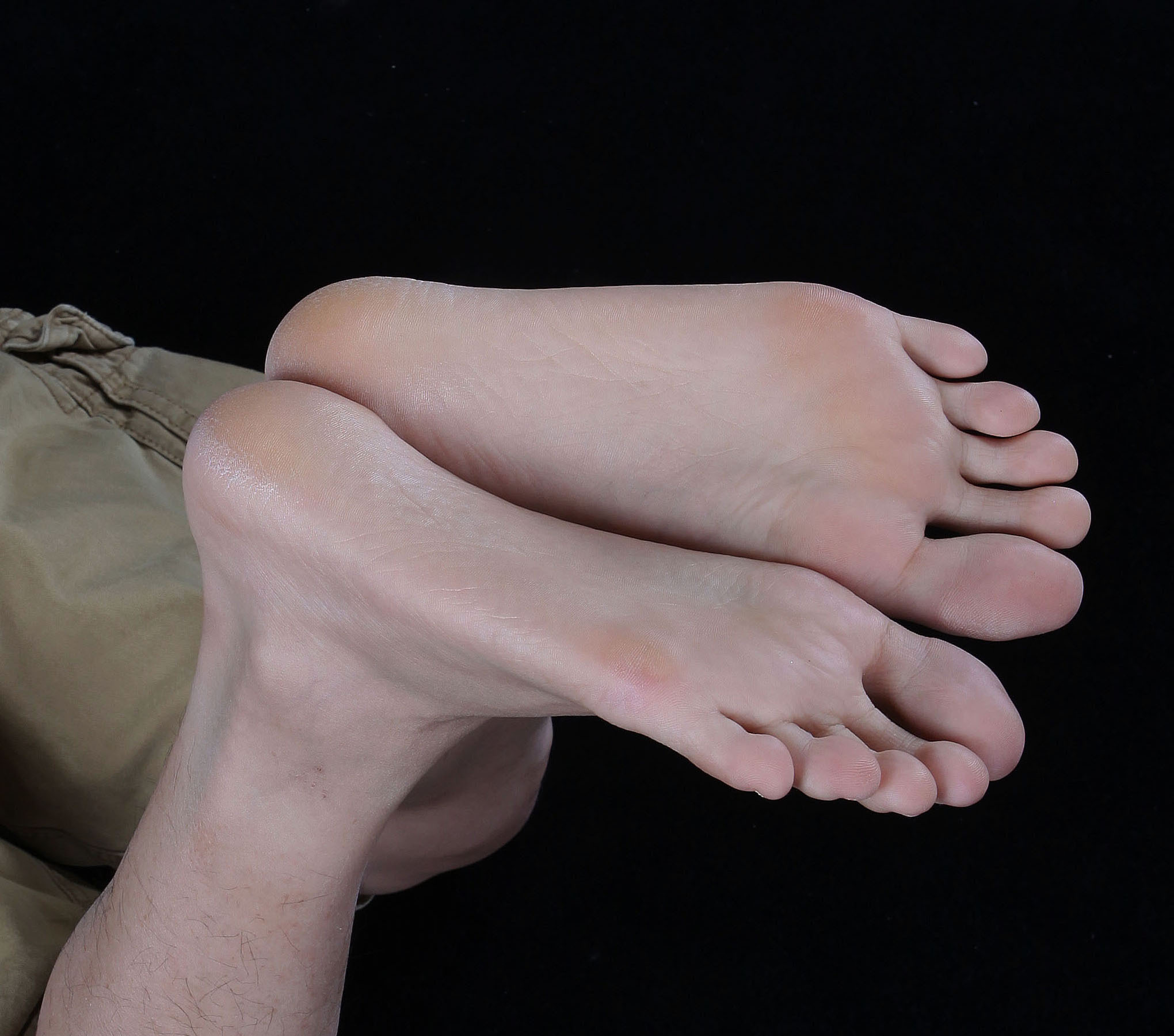 Adult bare soles in a clear close-up against a dark background.